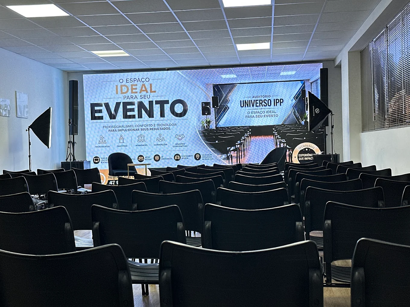 Auditório Universo IPP com cadeiras, palco, painel de LED e iluminação para eventos